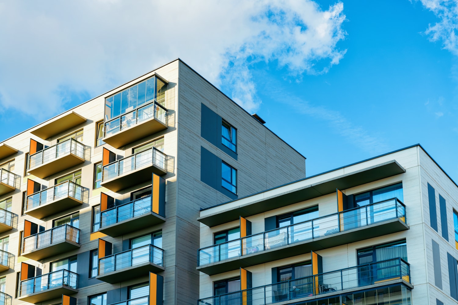Modern bostadsrättsförening med ljus fasad mot blå himmel en solig dag